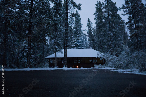 Cold scenery at a hut in the Canadian Rockies with snow and fire pit and pine trees in wonderful scenery and ice and blue rivers running through the scenery with snowy hut