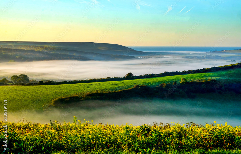 Cuckmere Valley Misty morning, the mist is hanging low in the valley and green rolling hills on either side are in morning sunshine