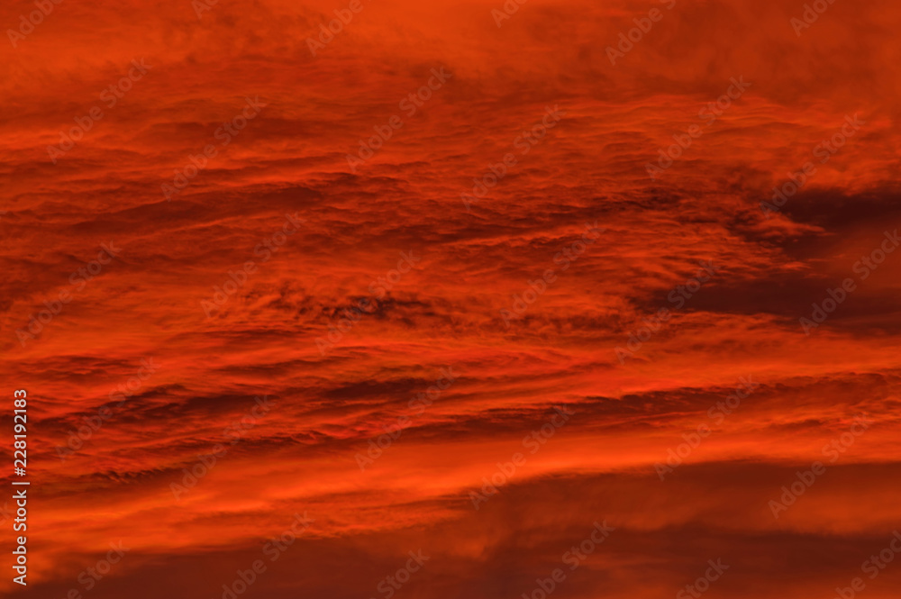 Naklejka premium Chmury zabarwione na czerwono światłem zachodzącego słońca.