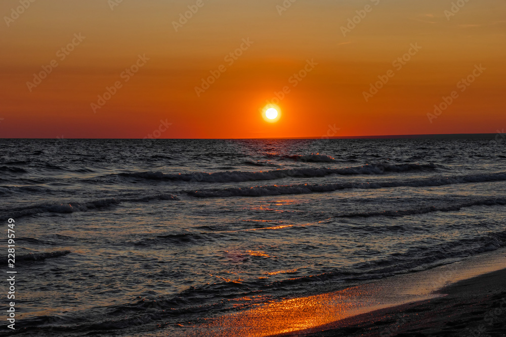 The sun sets over the horizon on the sea
