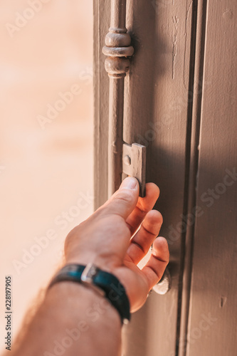 A man opens a vintage wooden shutters