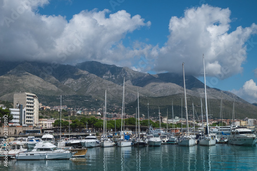 Boats and yachts in the harbor in Formia, with mountains and clouds in the background. 
