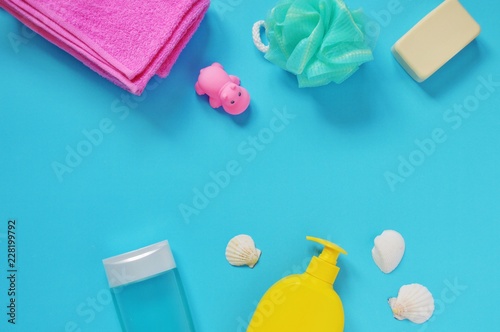 Flat lay baby bath products set. Pink terry towel, sponge, soap bar, shampoo, shower gel and seashells