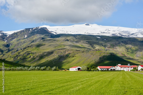 Eyjafjallajokull volcano in Iceland against blue summer sky with clouds. Farm Thorvaldseyri visible.