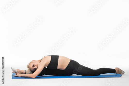Young slender woman sit on twine and stretching, isolated on white background