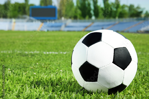 Soccer ball on fresh green football field grass. Space for text