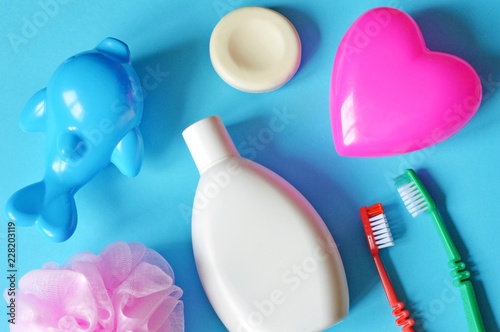 Flat lay shampoo, two colorful toothbrush, soap, sponge and pink heart shape box