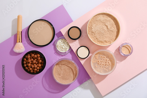 Flat lay composition with various makeup face powders on color background