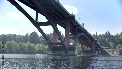 Slow motion footage of small boat in the distance, passing under a bridge photo