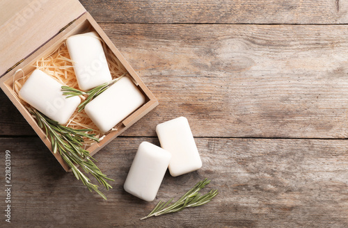 Flat lay composition with soap bars, rosemary and space for text on wooden background