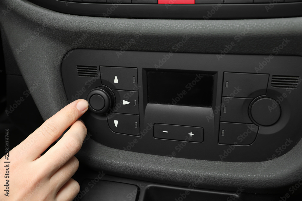 Woman adjusting air conditioner in car, closeup Woman adjusting air conditioner in car, closeup