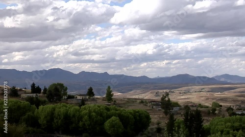 Time lapse of clouds over African Mountain Landscape with houses in the foreground. photo