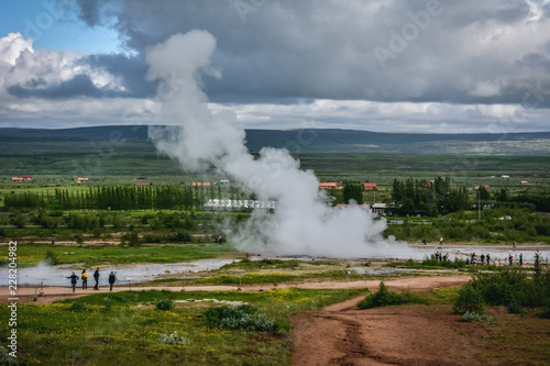 Eruption of Strokkur geyser in Iceland in summer with many tourists in the background