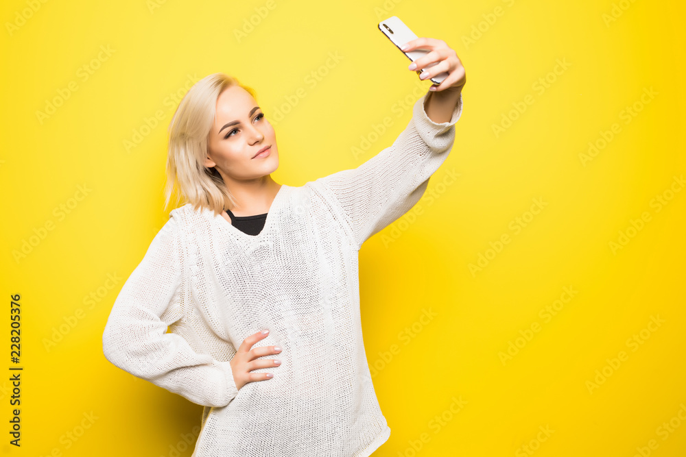 Portrait of cool cheerful girl having video-call with lover holding smart phone in hand shooting selfie on front camera isolated on yellow background e Portrait of cool cheerful girl having video-call with lover holding smart phone in hand shooting selfie on front camera isolated on yellow background e