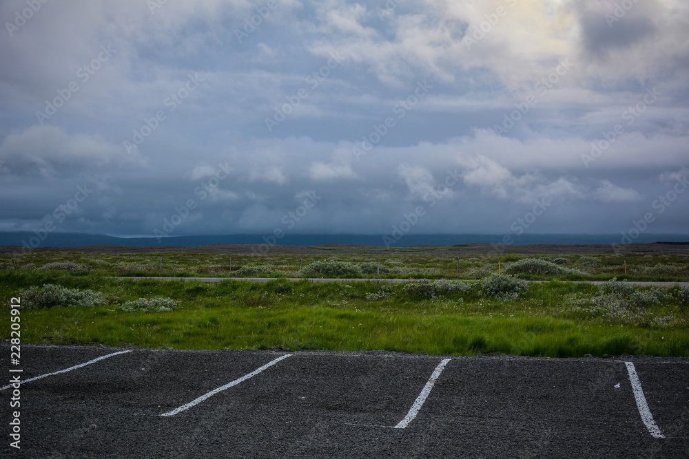 Meadow and empty parking lot with scenic sky near Gullfoss waterfall in summer in Iceland, Europe Meadow and empty parking lot with scenic sky near Gullfoss waterfall in summer in Iceland, Europe