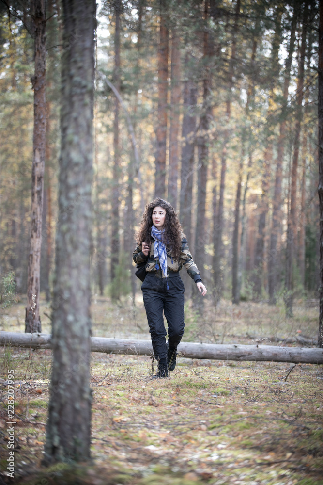 Portrait of happy woman with curly hair walkin among trees in an autumn. Joyful and smiles young woman having fun in the sunny fall park. Portrait of happy woman with curly hair walkin among trees in an autumn. Joyful and smiles young woman having fun in the sunny fall park.