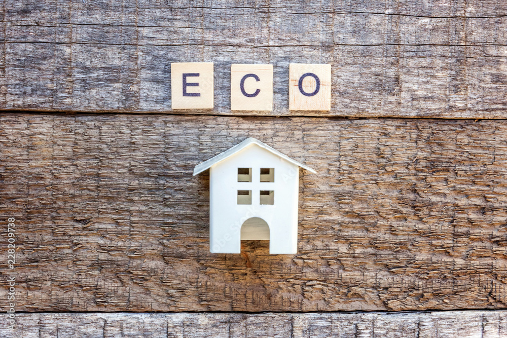 Miniature toy model house with inscription ECO letters word on wooden backdrop. Eco Village, abstract environmental background. Real estate mortgage property insurance sweet home ecology concept Miniature toy model house with inscription ECO letters word on wooden backdrop. Eco Village, abstract environmental background. Real estate mortgage property insurance sweet home ecology concept