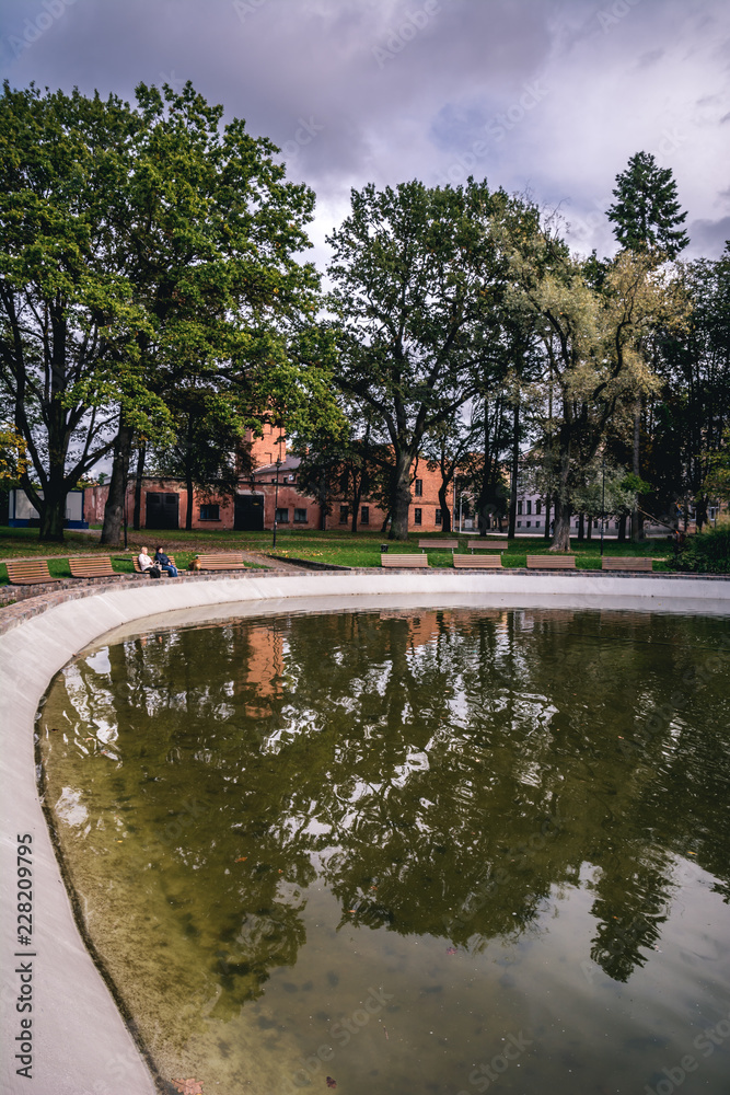 Dubrovina public park with green trees reflecting in a pond in Daugavpils, Latvia.