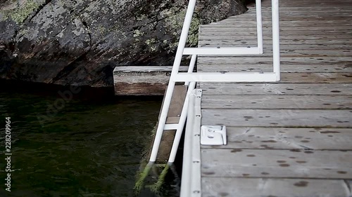 A pan of a swimming rail on a dock beside a lake. photo