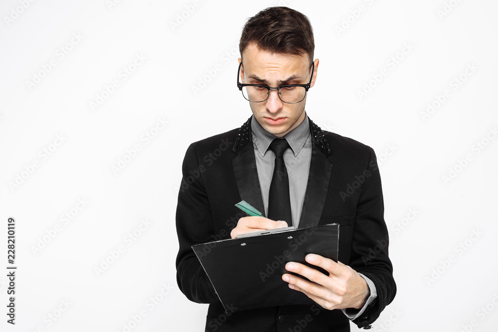 businessman in glasses and suit holding an empty sheet of paper, writing plans for the coming year, on a white background businessman in glasses and suit holding an empty sheet of paper, writing plans for the coming year, on a white background
