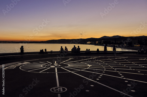 Sundial in Nice  France at sunset on Promenade des Anglais with outline of people. A famous place in French Riviera. 