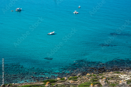 Beautiful white yachts in the turquoise sea near shore on a sunny summer day. San Giovanni di Sinis, Sinis peninsula, Cabras, Sardinia, Italy.