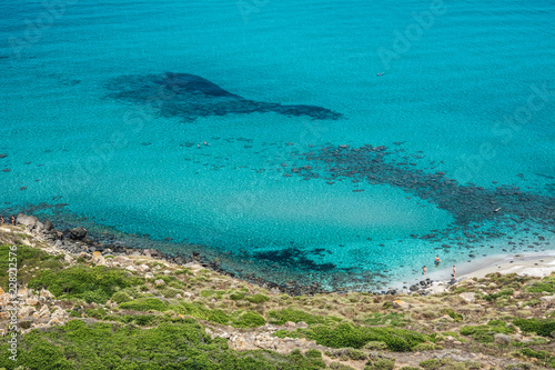 Beautiful turquoise sea and sea shore with few unrecognizable people resting on a sunny summer day. San Giovanni di Sinis, Sinis peninsula, Cabras, Sardinia, Italy.