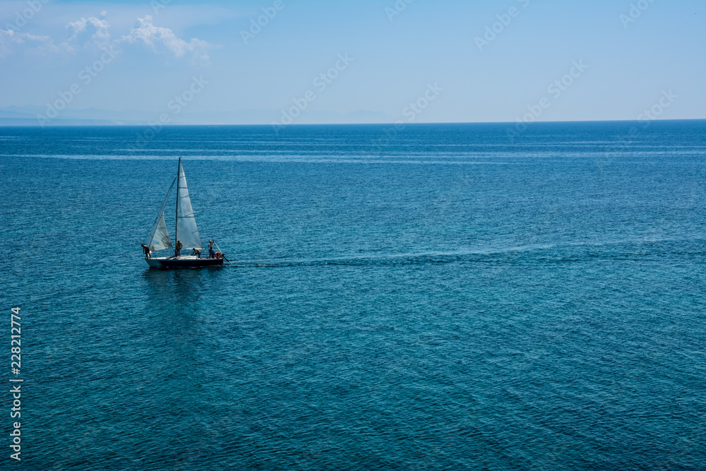 Fototapeta premium Sailing boat at an open turquoise sea with blue skies on a sunny summer day.