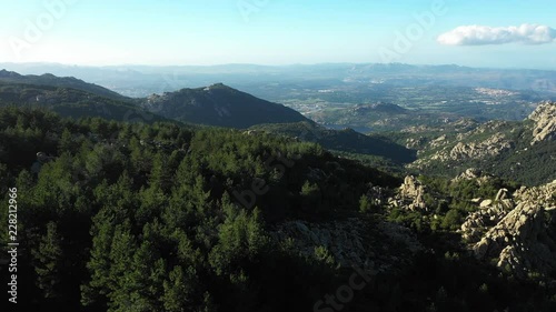 Video from above, aerial view of a beautiful valley surrounded by granite mountains and green vegetation, Monte Limbara, Sardinia, Italy. photo