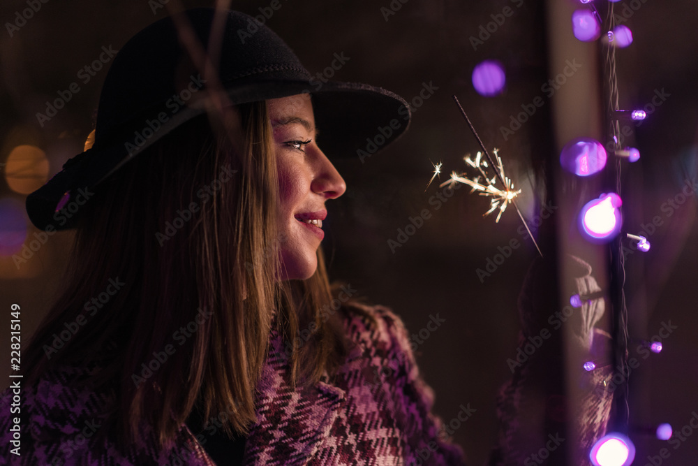 Young girl holding sparklers for christmas during winter alone in the park Young girl holding sparklers for christmas during winter alone in the park