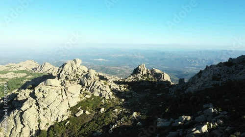 Video from above, aerial view of a beautiful valley surrounded by granite mountains and green vegetation, Monte Limbara, Sardinia, Italy. photo