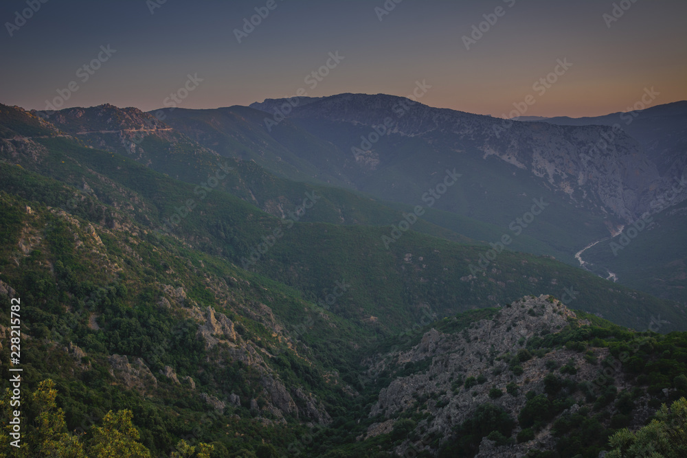 Panoramic Mountain Landscape view during a beautiful sunset, with layered blue mountains and river, Sardinia, Orosei region.
