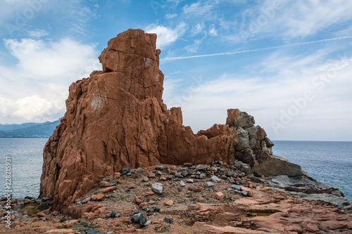 Red rocks of Arbatax city, Sardinia, Italy. Beautiful blue sky with some clouds and sea on a sunny summer day. Nobody in the scene.