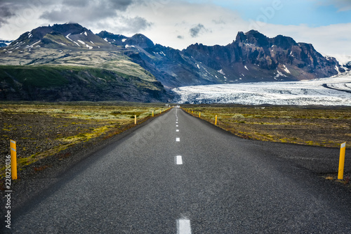 Empty asphalt road in Skeidararsandur with mountains and Vatnajokull glacier in background, Iceland in summer