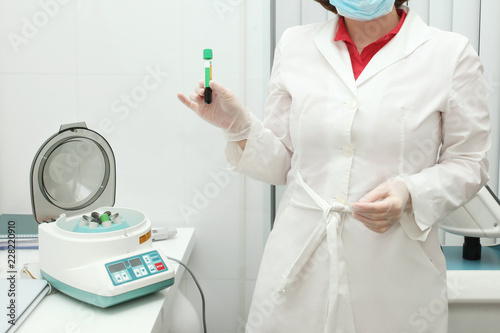 Doctor with a bottle of blood plasma and a centrifuge for plasmolifting