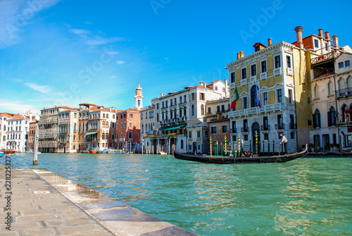 Gondola in front of Hotels on the Grand Canal in Venice Italy. Waterfront sidewalk in foreground.
