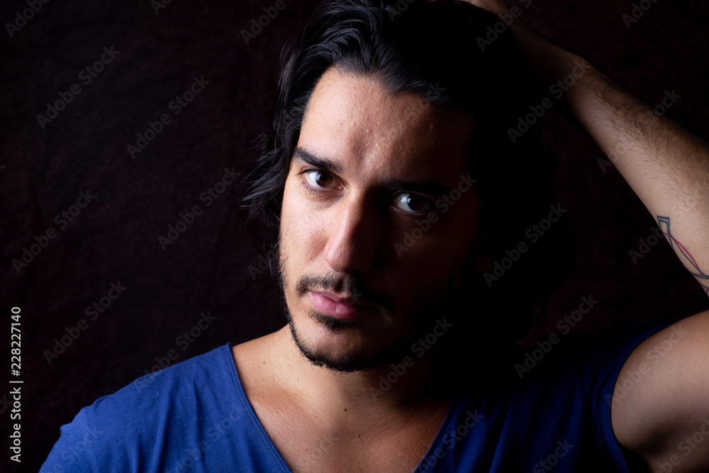 Moody portrait of man with black hair and blue t shirt Moody portrait of man with black hair and blue t shirt