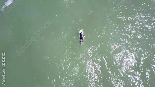 surfer girl in black on green sea joining another surfer photo