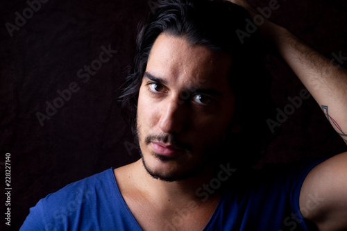 Moody portrait of man with black hair and blue t shirt