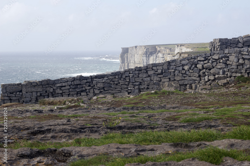 Beautiful view of the cliffs of Inis Mór under blue sky along the Atlantic Ocean from within the ancient fort of Dun Aengus (Dún Aonghasa) in Ireland