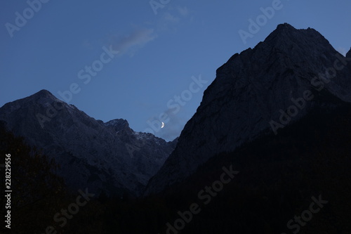 Evening crescent moon between mountains at Hammersbach in Bavaria Germany