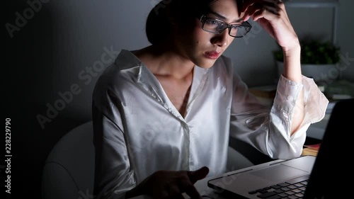 Woman working late at her home office. Beautiful asian woman talking on phone, got complaint from customer and getting stress, wearing glasses. Modern global connected business concept.