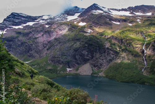 Fototapeta Naklejka Na Ścianę i Meble -  Man hiking gunsight pass trail in glacier national park, passing a small lake