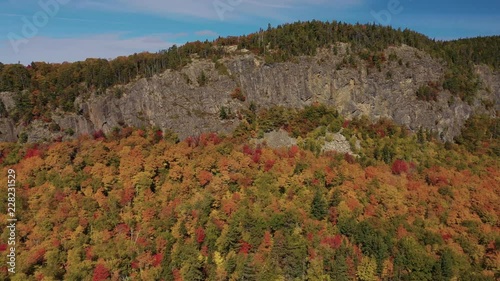 Aerial slide to the right along the cliff face of Kineo Mountain above a golden autumn forest photo