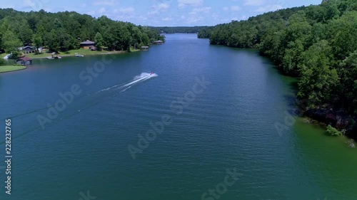 An aerial following a jet ski at it cruises through calm waters in 
