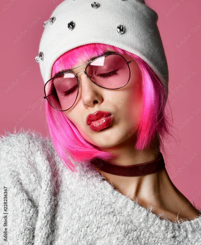 Fashion art photo of young grunge style woman with pink hair in clear modern sunglasses and white hat Fashion art photo of young grunge style woman with pink hair in clear modern sunglasses and white hat