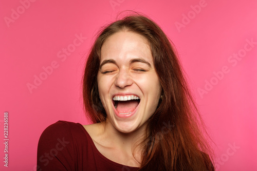 emotion face. happy thrilled joyful delighted woman young beautiful brown haired girl portrait on pink background.