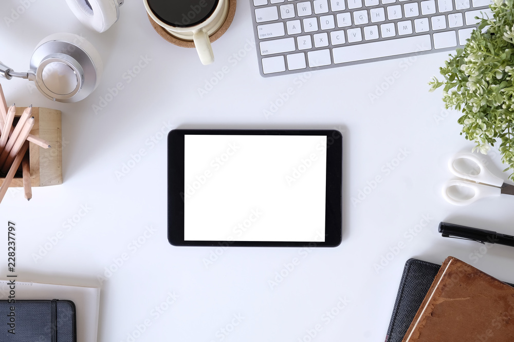 Top view workspace with mockup tablet on white table and office supplies.