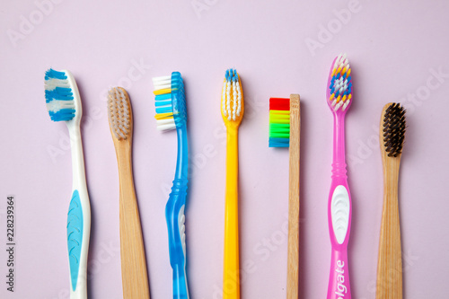 Many colored toothbrushes on purple background. How to choose toothbrush