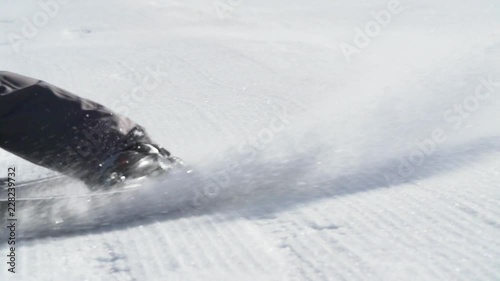 Close up slow motion skis turning on groomer